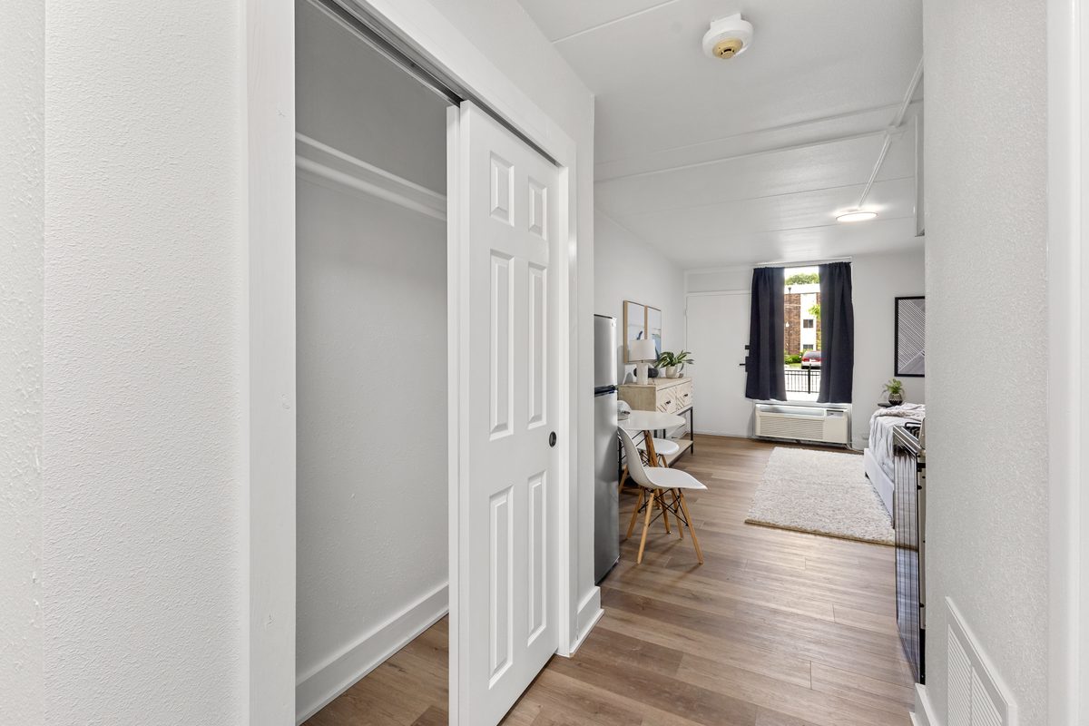 The entry of an apartment with a sliding closet door and the living area beyond.