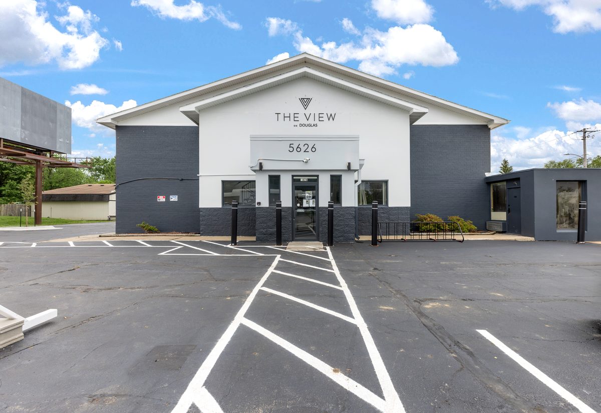 The front of the building from Douglas Avenue, with the property sign above the entrance and the striped parking lot in front.
