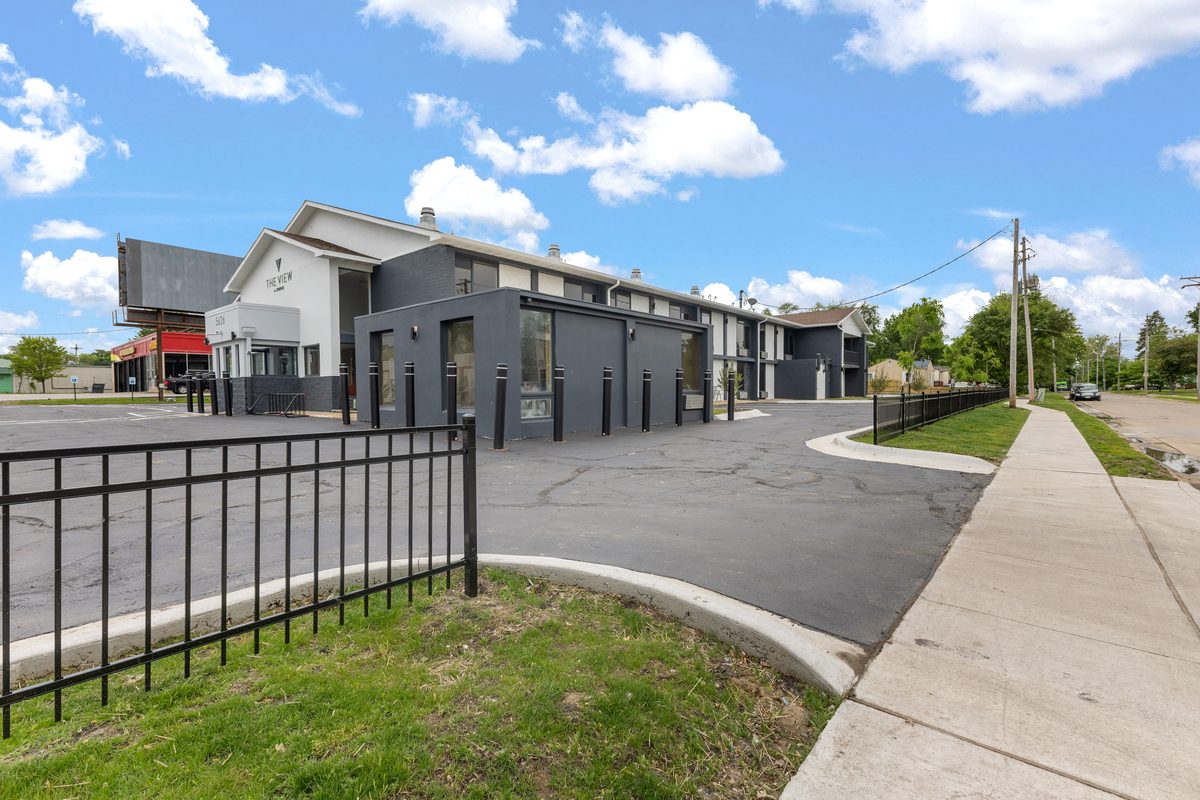 The two-story building behind new black steel fencing, with fresh sidewalk and landscaping.